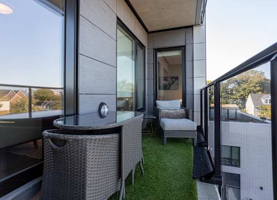 A balcony with a table and chairs overlooking a residential area.