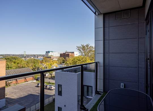 A view from a balcony of a building with a white brick building in the distance.
