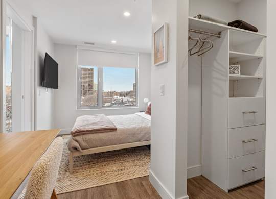 A bedroom with a bed, a TV, and a wardrobe.
