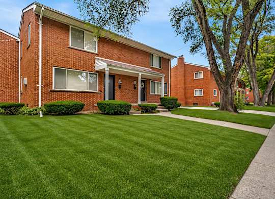 A red brick house with a green lawn in front.
