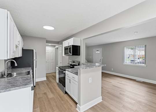 A kitchen with white cabinets and a black countertop.