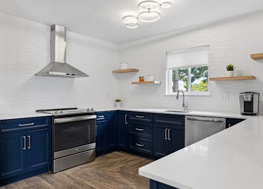 A modern kitchen with dark blue cabinets and stainless steel appliances.