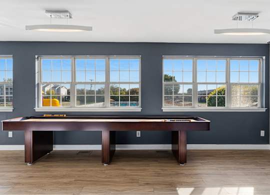 A room with a pool table and a view of the outside through the windows.