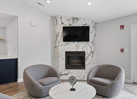 A living room with a fireplace and two grey armchairs.
