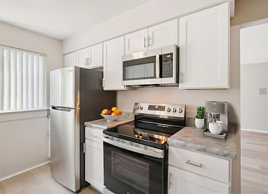 A modern kitchen with a stainless steel refrigerator, white cabinets, and a black oven.