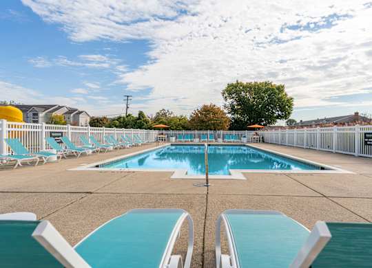 A large outdoor swimming pool with blue water and white lounge chairs.