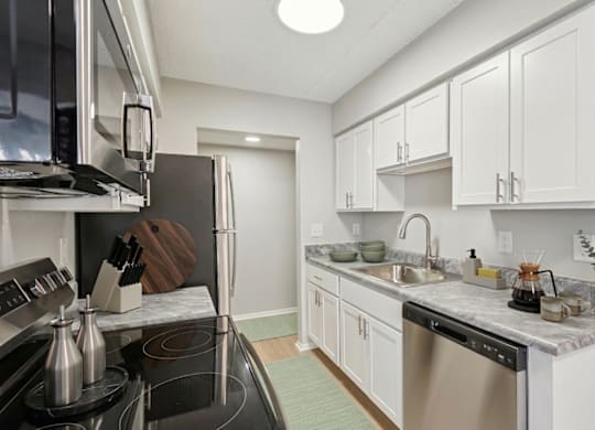 A kitchen with white cabinets and a black stove top.