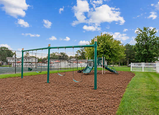 A playground with a green swing set and a green slide.
