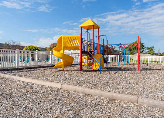 A playground with a yellow slide and red and blue play structures.