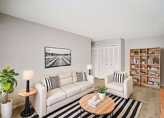 A living room with a white couch, a coffee table, and a bookshelf.