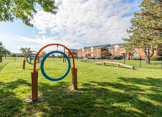 A playground with a blue and red ring structure and a bench.