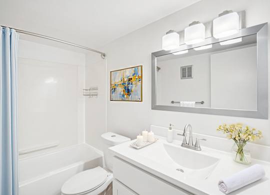A white bathroom with a toilet, sink, and mirror.