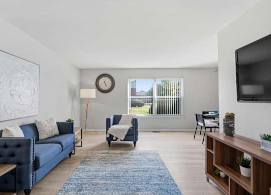 A living room with a blue couch and a wooden floor.