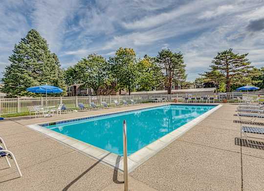A large outdoor swimming pool surrounded by trees and lounge chairs.