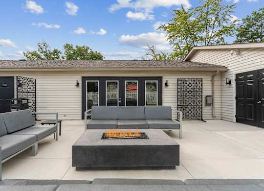 A modern house with a grey sofa and a fire pit in the front yard.