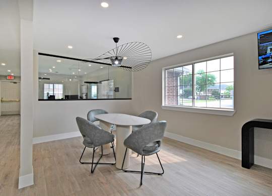A modern dining room with a round table and grey chairs.