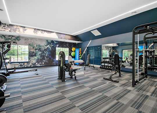 A gym with a variety of equipment including treadmills, weights, and exercise machines.