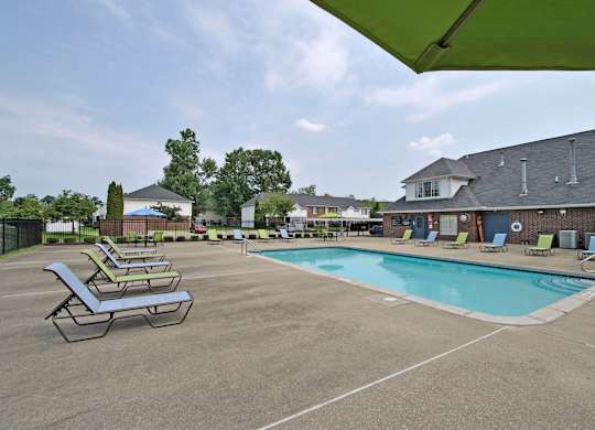 A pool area with sun loungers and a green umbrella.