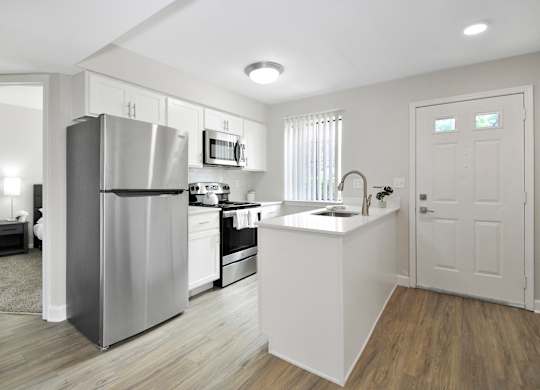A modern kitchen with a stainless steel refrigerator and white cabinets.