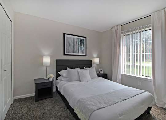 A bedroom with a large bed and a framed picture on the wall.