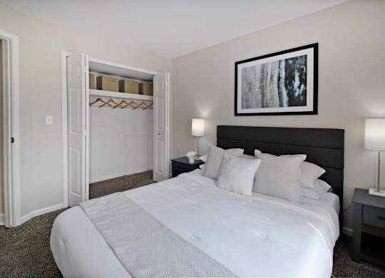 A bedroom with a large bed and a painting on the wall.