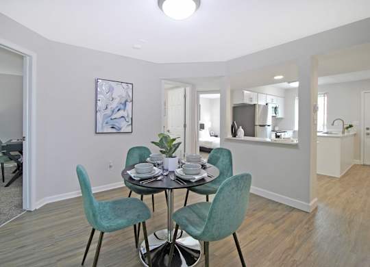 A dining room with a table set for two and a painting on the wall.