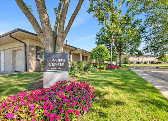 A sign for Cambridge on Ford Apartments is displayed in front of a landscaped area.