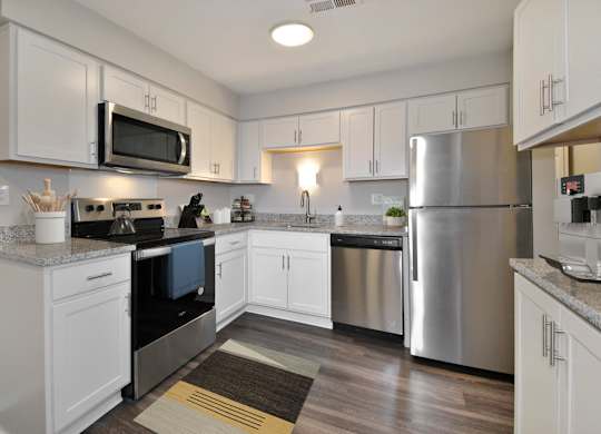 A kitchen with white cabinets and a stainless steel refrigerator.