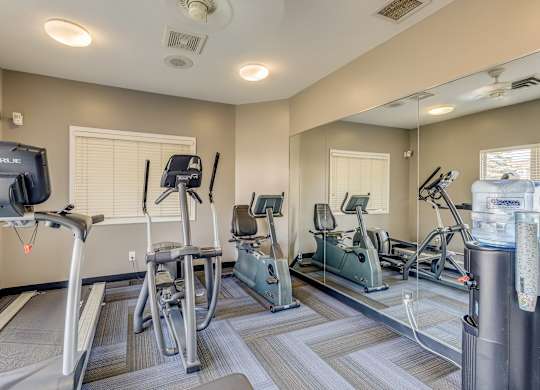 A gym with treadmills, exercise bikes, and a television.