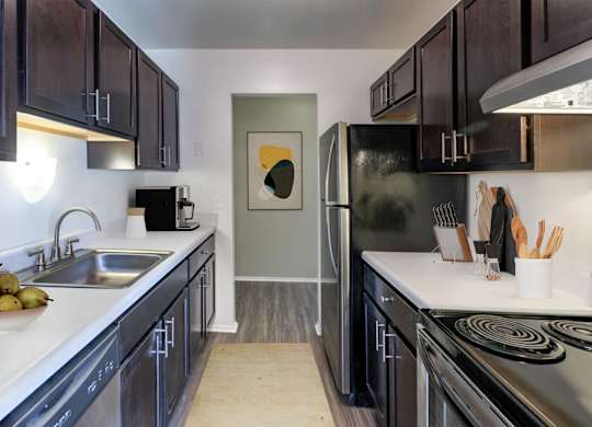 A kitchen with black cabinets and a stainless steel refrigerator.