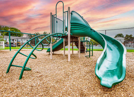 A playground with a green slide and a climbing frame.