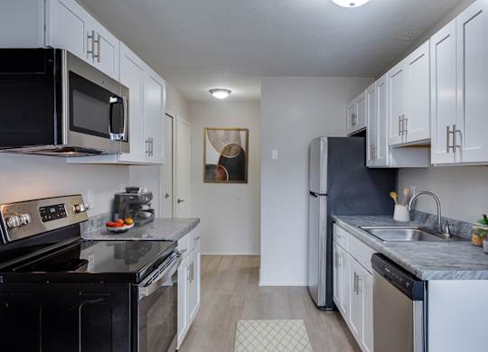 A kitchen with black appliances and white cabinets.