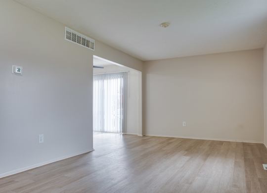 A room with wooden flooring and a window on the right side.