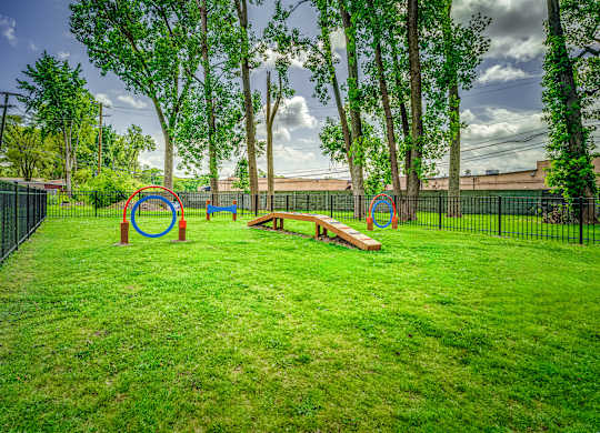 A playground with a green lawn and a black fence.