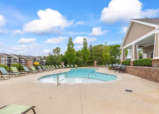 A swimming pool surrounded by lounge chairs and a building in the background.