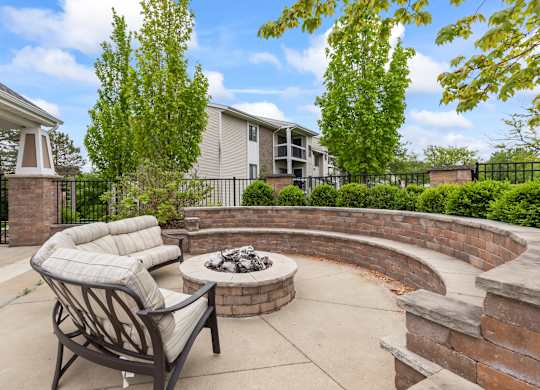 A patio with a fire pit and a chair.