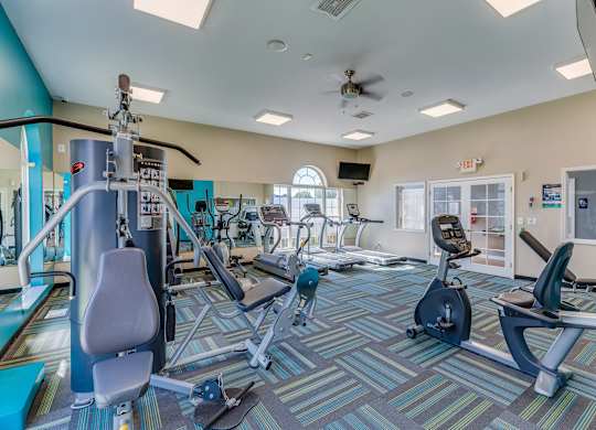 A gym with a variety of equipment including treadmills, stationary bikes, weights, and exercise machines.
