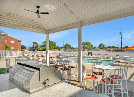 A poolside area with a grill and seating area.