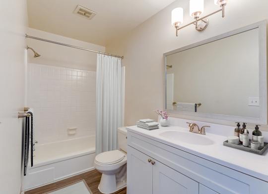 A white bathroom with a toilet, sink, and mirror.