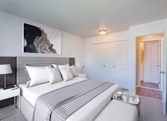 A bedroom with a large bed and a painting on the wall.