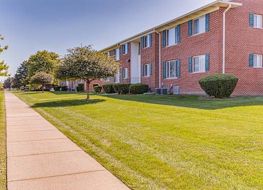 A red brick building with a green lawn in front.