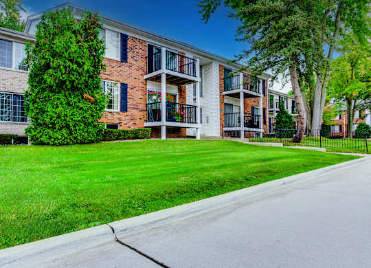 A row of apartment buildings with green lawns in front.