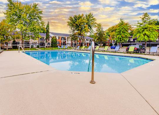 A swimming pool surrounded by trees and a fence.