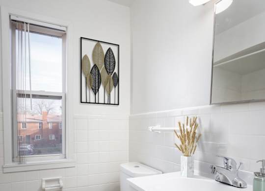 A white bathroom with a toilet, sink, and mirror.