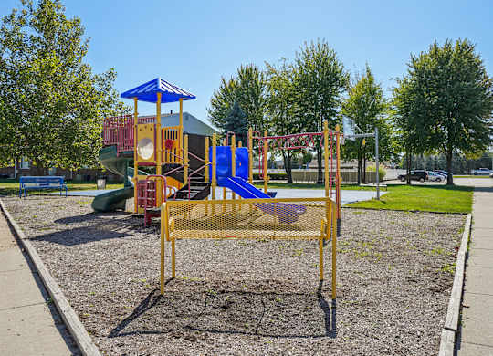 A playground with a blue and yellow swing set.