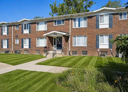 A brick apartment building with a green lawn in front.