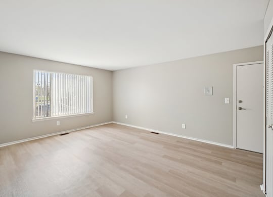 A room with wooden flooring and a window with blinds.