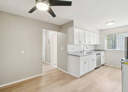 A kitchen with white cabinets and a ceiling fan.
