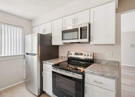 A kitchen with a stove, oven, refrigerator, and microwave.