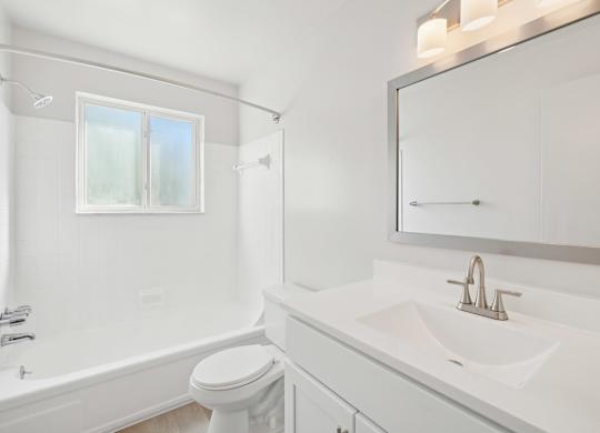 A white bathroom with a toilet, sink, and bathtub.